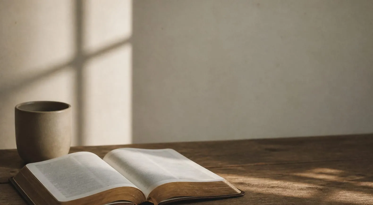 An open Bible and a cup on a sunlit table